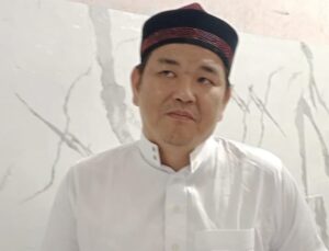 Ustadz Hasan Basri Fuk memakai baju putih dan peci hitam maroon saat memberikan tausiah tentang integritas dan amanah informasi