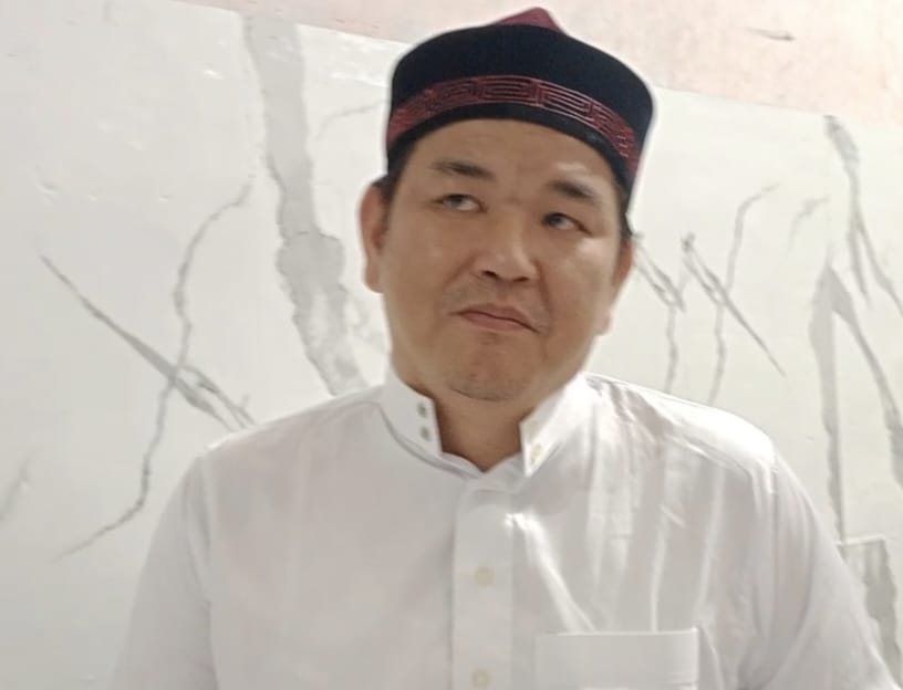 Ustadz Hasan Basri Fuk memakai baju putih dan peci hitam maroon saat memberikan tausiah tentang integritas dan amanah informasi